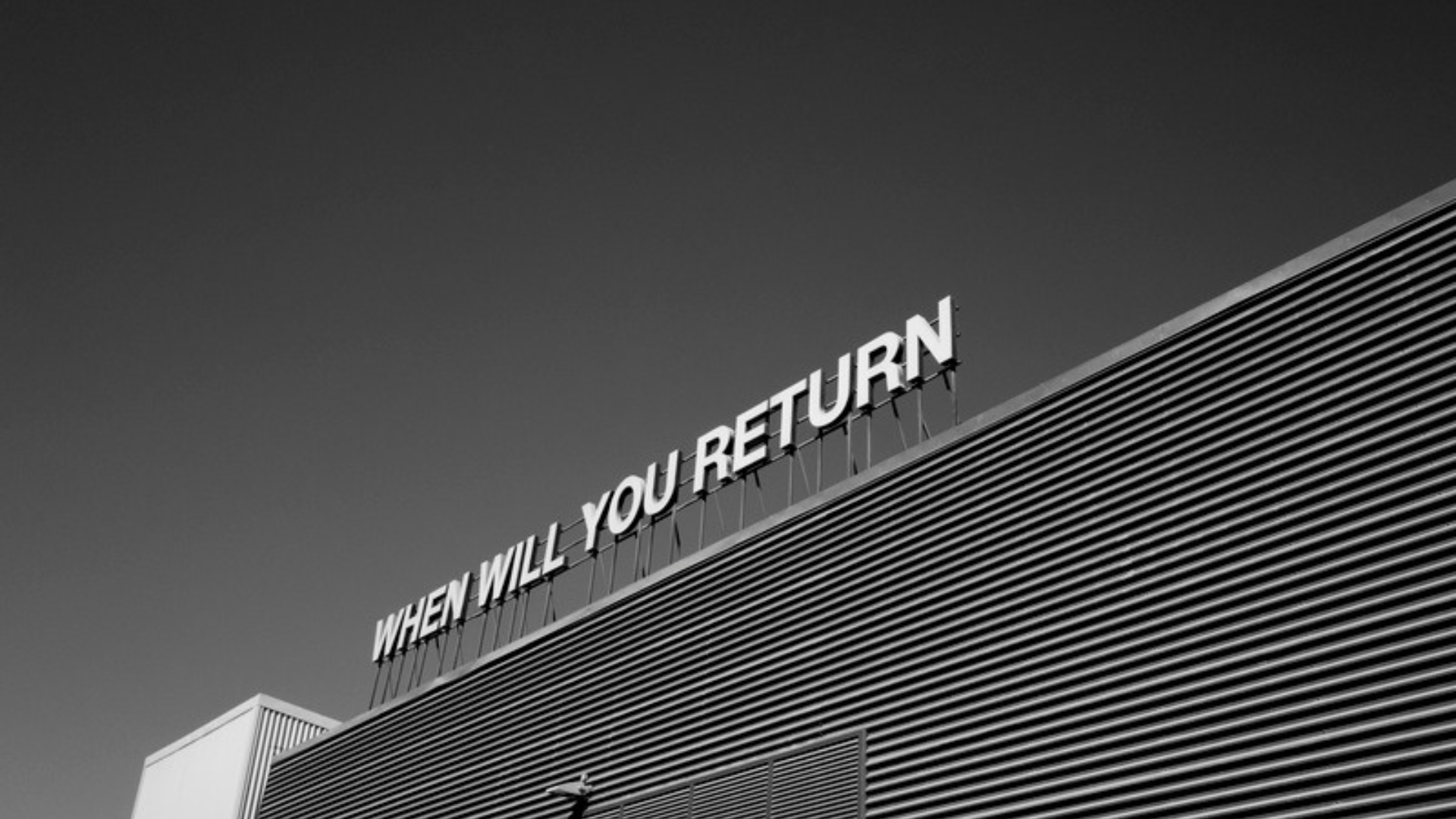 Beitragsbild zum Impuls: Ein Konzern und darüber ein Schild mit der Aufschrift: "When will you come back"